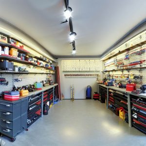 an image that showcases a panoramic view of a well-organized garage. It would be fantastic to see a neat space with items neatly arranged on wall-mounted storage like pegboards and slatwalls, overhead storage bins clearly labeled, and tools hanging from hooks. On the floor, there could be labeled bins and boxes, and in the corner, a set of corner shelves.