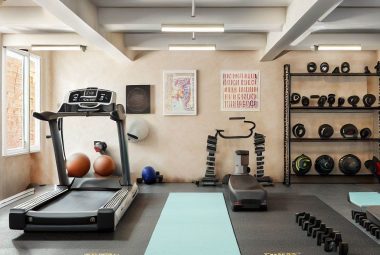 An image of a personal gym in a converted garage. The garage gym ideas includes diverse equipment like a treadmill, weights, and a yoga mat neatly arranged. There is clear floor space for workouts, and the walls feature motivational posters.